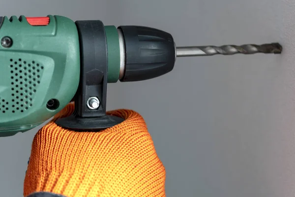 workman with a hammer drill. Hands in protective gloves with hammer drill perforator. close-up