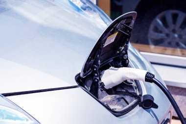 Elektrikli bir arabaya takılı güç kaynağını kapatın. Elektrikli bir arabanın güç prizinin görüntüsünü kapatın, şarj oluyor. Çevre dostu alternatif enerji kavramı