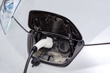 Elektrikli bir arabaya takılı güç kaynağını kapatın. Elektrikli bir arabanın güç prizinin görüntüsünü kapatın, şarj oluyor. Çevre dostu alternatif enerji kavramı