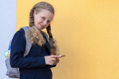 Kızın elinde akıllı telefon var. Çocukların alet kullanması kavramı, tablet ve aletlerle ilgili sorunlar. Üniformalı kız. Boşluğu kopyala