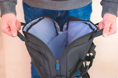 Yakın plan. Elinde torba, elinde açık bir çanta, boş çanta konsepti, dizüstü bilgisayar için koruyucu klasör. Adam boş bir çanta tutuyor.