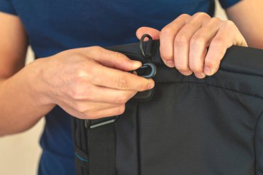 Yakın plan. Eller plastik bir karabinaya. Adam kemeri çantaya bağlıyor. Adam kemer bağlayıcıyı elinde tutuyor. bir dizüstü bilgisayar için koruyucu bir dizin. 