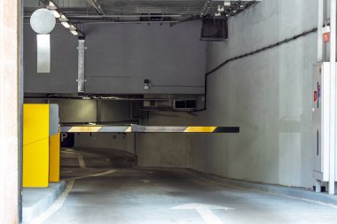 Otoparkın girişi. Yeraltı otoparkında bir bariyer. İşaret panosu ve ayrıntıları olan bir park.