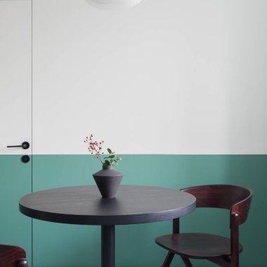 Modern yemek odası. Süslü, siyah ve yuvarlak yemek masası. Dekoratif vazosu ve koyu ahşap koltuğu var.