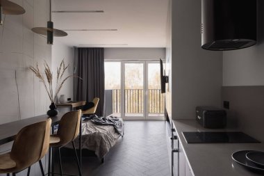 Ahşap zemin ve pencere duvarı olan açık stüdyo dairede küçük ve şık bir mutfak.