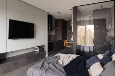 Şık ve küçük bir stüdyo daire, yatak odası, televizyonu açık mutfak ve duşu cam duvarın arkasında.