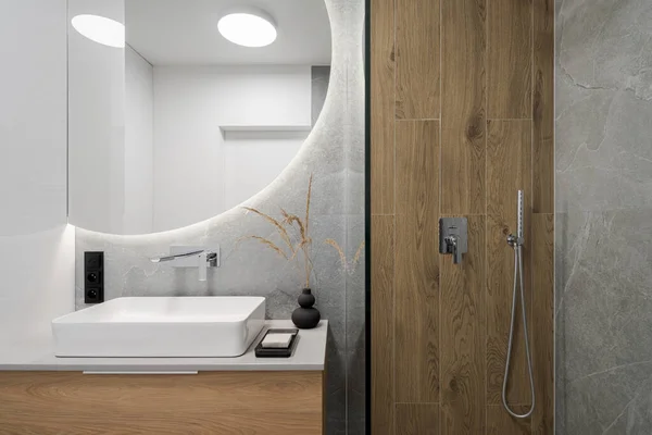 洗澡间里的现代浴室 旁边是一个大的圆形镜子 上面有洗澡盆上方的铅灯 — 图库照片