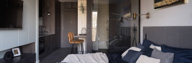 Küçük ve modern stüdyo daire panoraması açık yatak odası, cam duvarın arkasında banyo ve koridorda mutfak.