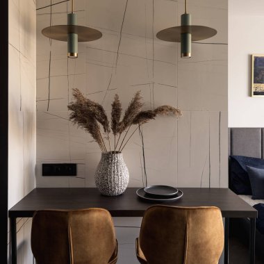 İki modern lambanın ve iki altın koltuğun altında süslemeleri olan şık bir masaya yakın plan.