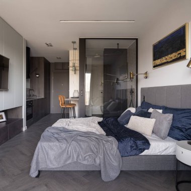 Büyük ve rahat bir yatak, cam duvarın arkasında banyo modern ve şık, küçük, açık bir daire.