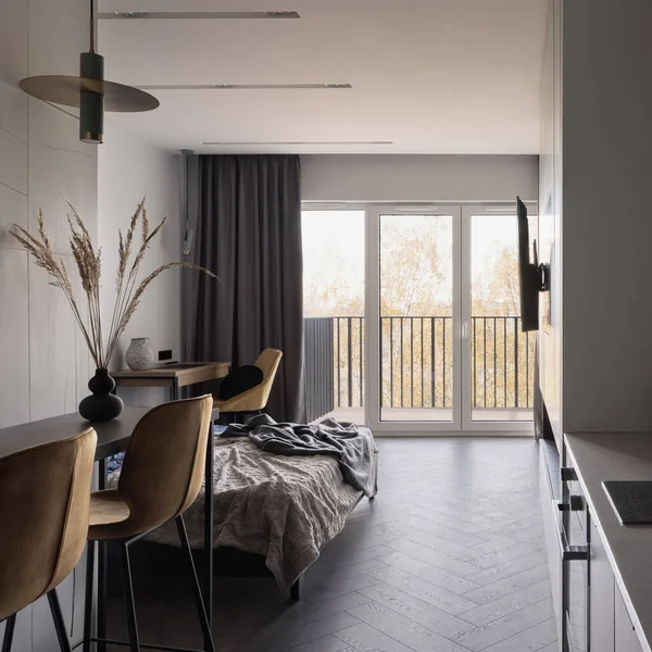 Açık stüdyo dairede, ahşap zemin ve büyük pencere duvarı olan küçük bir masa.