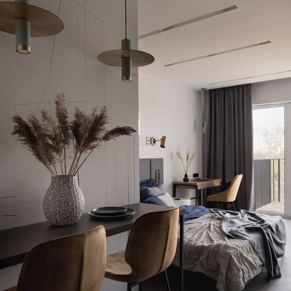 Стильный и маленький стол с украшениями, два желтых стула под двумя современными лестницами рядом со спальней