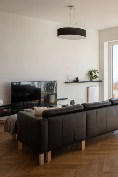 テレビと大きな 黒のコーナーソファ付きのモダンなリビングルーム — ストック写真