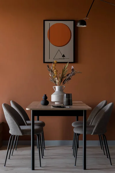 Eclectic dining room with art on modern rusty colored wall, simple table with four elegant chairs