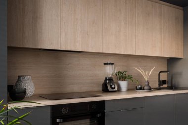 Small kitchen with wooden and gray furniture, black oven and induction hob and black tap