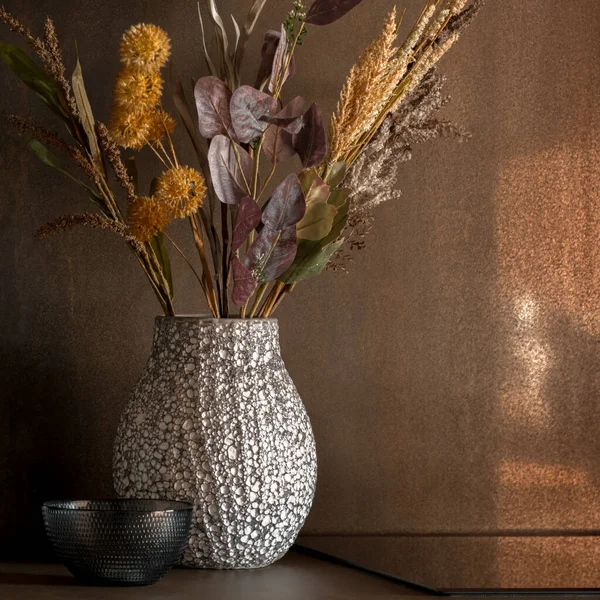 Close-up on decorative white and gray vase with dried flowers
