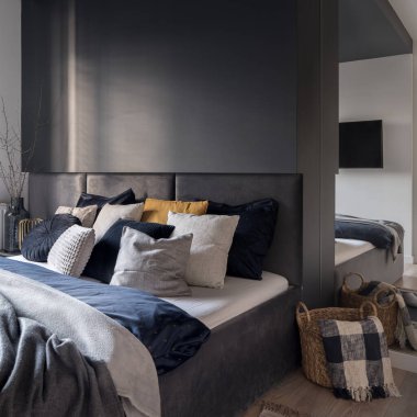 Stylish bedroom with cozy bed with nice bedclothes and pillows, big mirror and decorations