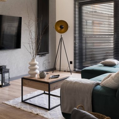Süslü dekorları olan küçük bir oturma odası ve siyah panjurlu büyük bir pencere.