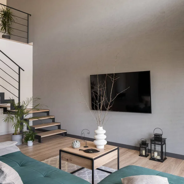 装飾されたコーヒーテーブルと木製の階段と現代のリビングルームのコンクリート壁に大きなテレビ — ストック写真
