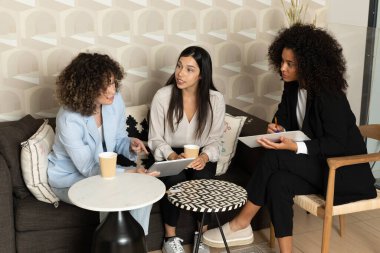 Ofisteki bir kanepede oturup birlikte çalışan mutlu iş kadınları. Ofis kavramı.