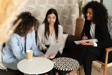 Ofisteki bir kanepede oturup birlikte çalışan mutlu iş kadınları. Ofis kavramı.