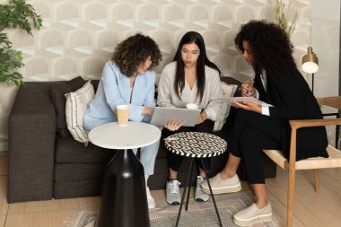 Ofisteki bir kanepede oturup birlikte çalışan mutlu iş kadınları. Ofis kavramı.