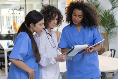 Young female medical work team wearing blue uniform smiling and looking at each other.