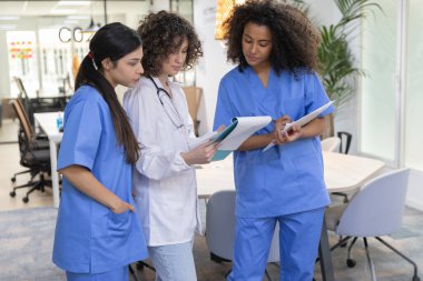 Young female medical work team wearing blue uniform smiling and looking at each other.