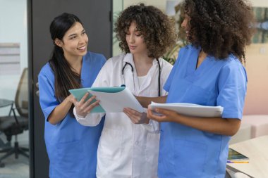 Young female medical work team wearing blue uniform smiling and looking at each other.