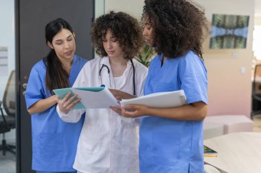 Young female medical work team wearing blue uniform smiling and looking at each other.