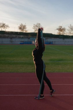 Koşu pistindeki genç sporcu esneme ve egzersiz yapıyor.