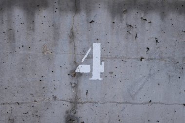 Siyah noktalı ve yatay çatlaklı beton bir duvarın üzerinde dört numara.