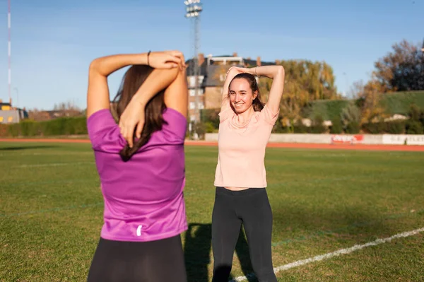 Dos Mujeres Jóvenes Haciendo Estiramiento Hierba Una Pista Atletismo Antes — Foto de Stock