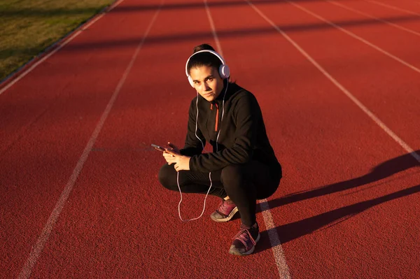 Young Woman Athlete Looks Mobile Headphones Athletics Track — Fotografia de Stock