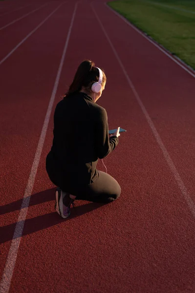 Young Woman Athlete Looks Mobile Headphones Athletics Track — Foto de Stock