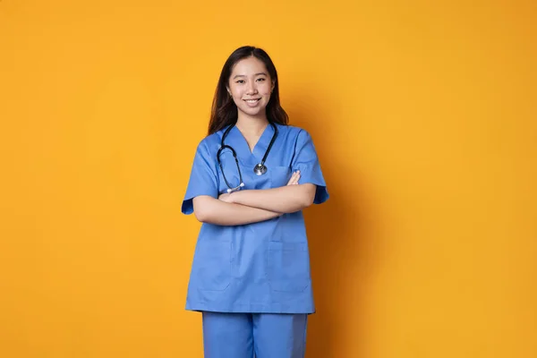 Studio Fotografie Oranžovým Pozadím Asijského Lékaře Uniformě Stojící Rukama Zkříženýma Stock Obrázky