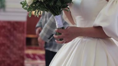 The bride is holding a large bouquet in her hands, close-up
