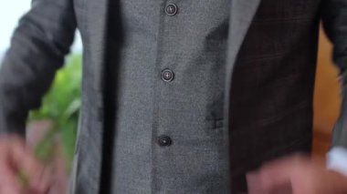 A businessman puts on a jacket, a business person fastens a button
