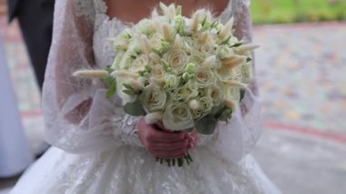 The bride is holding a large bouquet in her hands, close-up