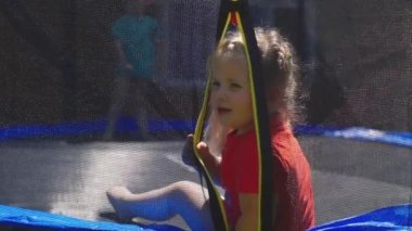 A child on a trampoline. The little girl is smiling