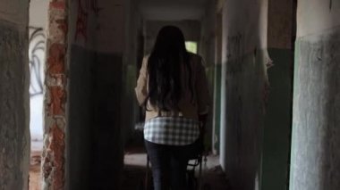 Korkunç binalar ve kalıntılar, Ukrayna 'daki savaşın bir sonucu, yıkılmış bir ev, koridorda yürüyen bir anne, bir çocukla birlikte bir bebek arabası taşıyor.