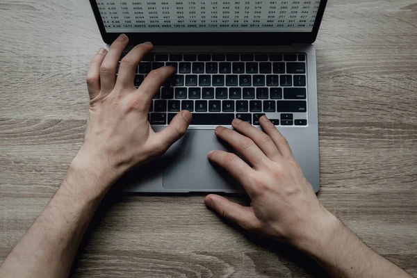 Las manos masculinas están escribiendo en un teclado portátil. El hombre de negocios trabaja remotamente desde casa. Freelancing en línea. — Foto de Stock