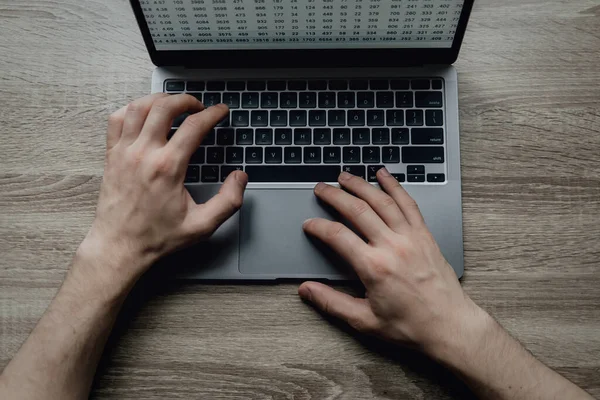 Las manos masculinas están escribiendo en un teclado portátil. El hombre de negocios trabaja remotamente desde casa. Freelancing en línea. — Foto de Stock