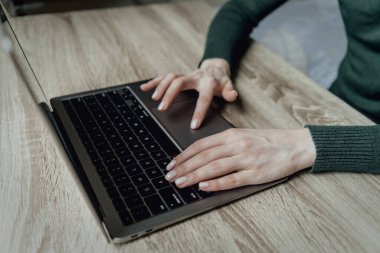 Genç bir kadının elleri dizüstü bilgisayarda yazı yazıyor. Evde çalışma alanı işi. Kız öğrenci. Çevrimiçi iş ve serbest çalışma. Mesafe öğrenme. Sayılar ve metinlerle çalış.