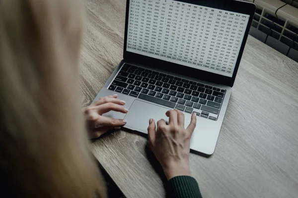 Las manos de una mujer joven están escribiendo en un portátil. Trabajo en el espacio de trabajo en casa. Estudiante. Negocios en línea y freelancing. Enseñanza a distancia. Trabajar con números y texto. — Foto de Stock