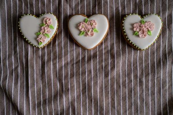 Biscoitos de gengibre branco com cereja e decoração de flores em uma toalha listrada. Fundo para o Dia Internacional das Mulheres ou Dia dos Namorados. — Fotografia de Stock
