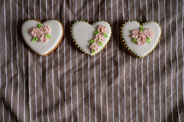 Biscoitos de gengibre branco com cereja e decoração de flores em uma toalha listrada. Fundo para o Dia Internacional das Mulheres ou Dia dos Namorados. — Fotografia de Stock