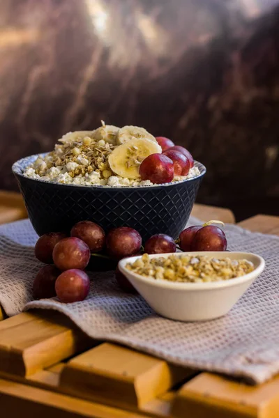 Bir tabak süzme peynir, müsli, yulaf ezmesi, üzüm ve muz. Protein diyeti kahvaltısı. Kahvaltıda sağlıklı ve lezzetli yemekler.