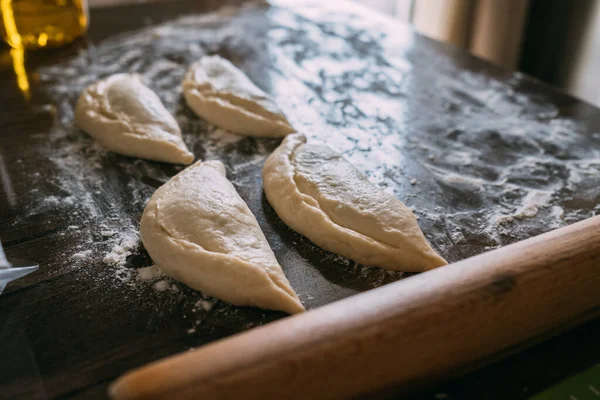 As tortas feitas à mão e um rolo põem-se na farinha. — Fotografia de Stock