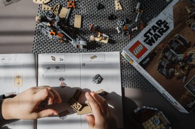 21.03.2022. Batumi, Georgia. Çocuk, Lego inşaatçısını elle masaya yatırıyor. Üst Manzara. Yıldız Savaşları. Disney